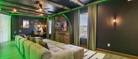 A room with a long couch, a desk, and a TV mounted on the wall.