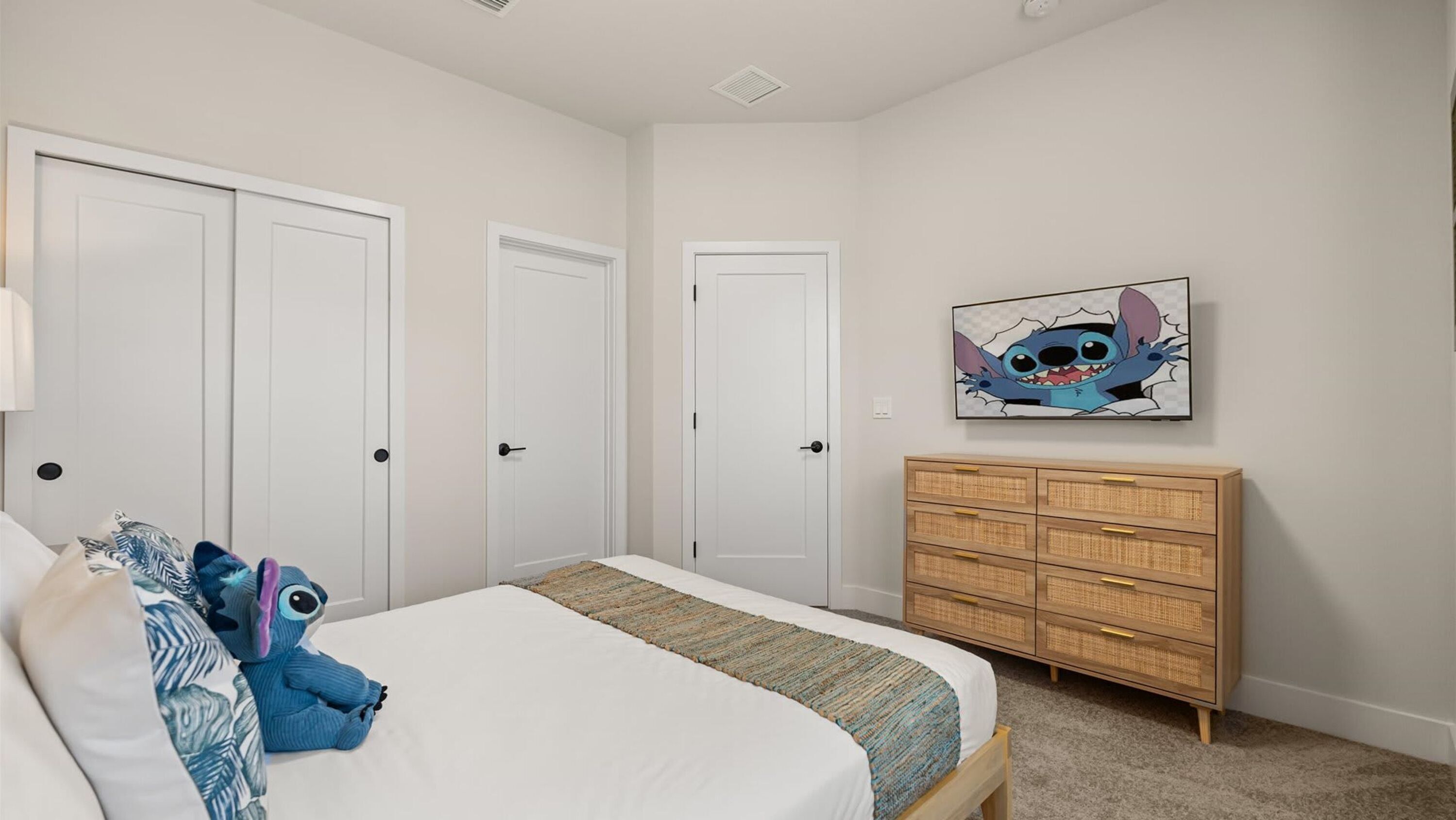 A bedroom with a bed, a dresser, and a wall-mounted picture.