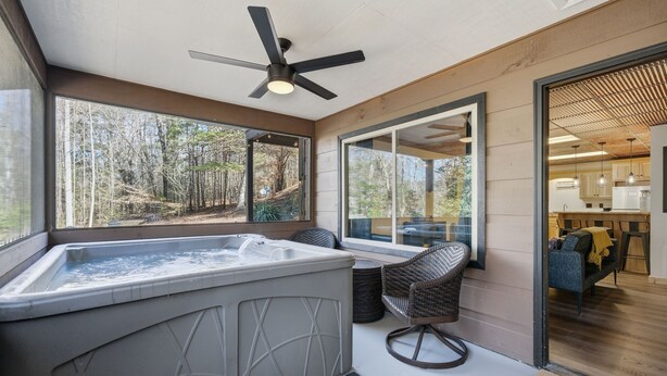 Ein modernes Badezimmer mit freistehender Badewanne, Deckenventilator und großen Fenstern mit Blick auf den umliegenden Wald.