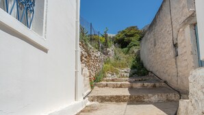 A narrow stone staircase leading up to a building with a white exterior and blue window bars. - Holiday Home 'Hippocrates' with Mountain View, Wi-Fi and Air Conditioning (Amorgos)