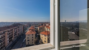 A high-rise building with multiple floors, large windows, and a view of a cityscape with various buildings and a clear sky.