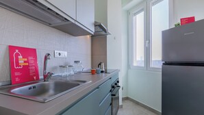 A modern kitchen with stainless steel appliances, a double sink, and a window providing a view of the city.