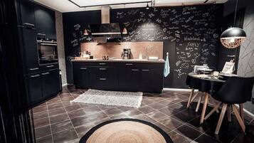 Een koelkast, een oven, een kookplaat, kookgerei, borden en bestek