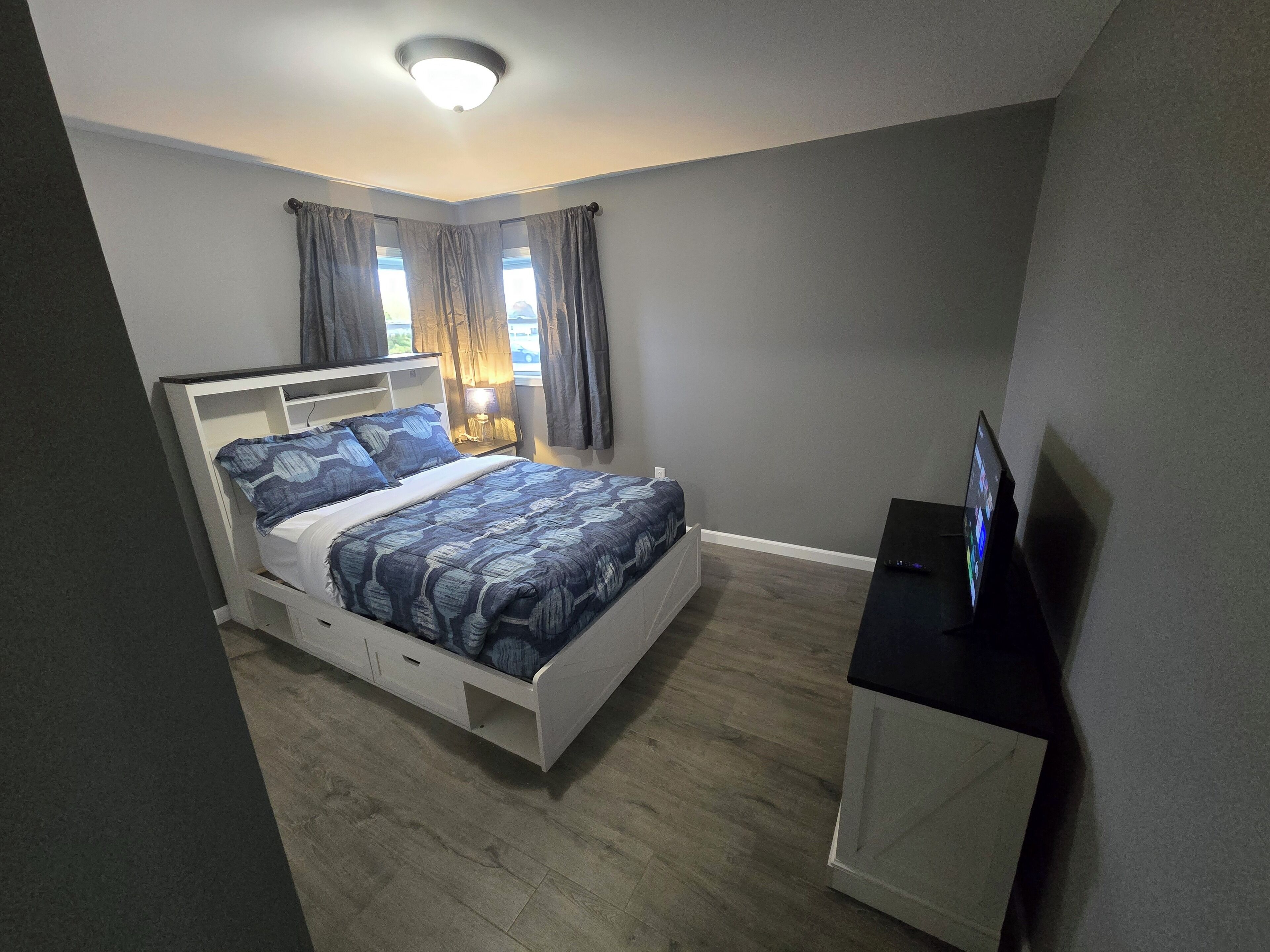 A bedroom with a bed, a desk, and a lamp.
