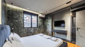 A modern bedroom with a large bed, a TV mounted on the wall, and a window with a view of the outside. - GOA Apartment 2 by Kondo Stays (Tiranë)