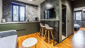 A modern kitchen with a TV, bar stools, and a wooden dining table. - GOA Apartment 2 by Kondo Stays (Tiranë)