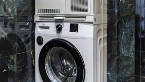 A stacked washer and dryer unit in a bathroom with dark marble tiles. - GOA Apartment 2 by Kondo Stays (Tiranë)