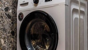 A front view of a compact, modern washing machine with a control panel and a digital display.