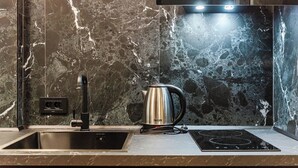 A modern kitchen with a black sink, a DeLUX kettle, and a built-in induction cooktop.