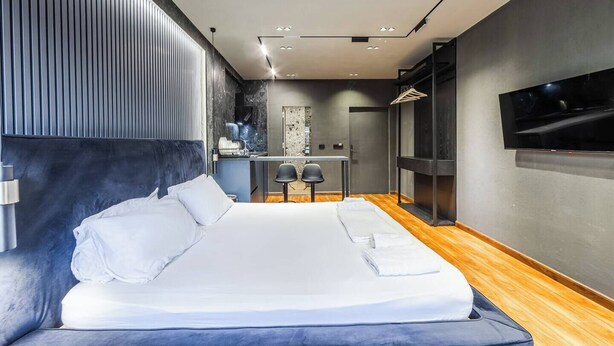 A modern hotel room with a large bed, a desk, and a TV.