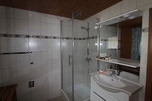 A bathroom with a glass-enclosed shower, a white sink, and a mirror above the sink.