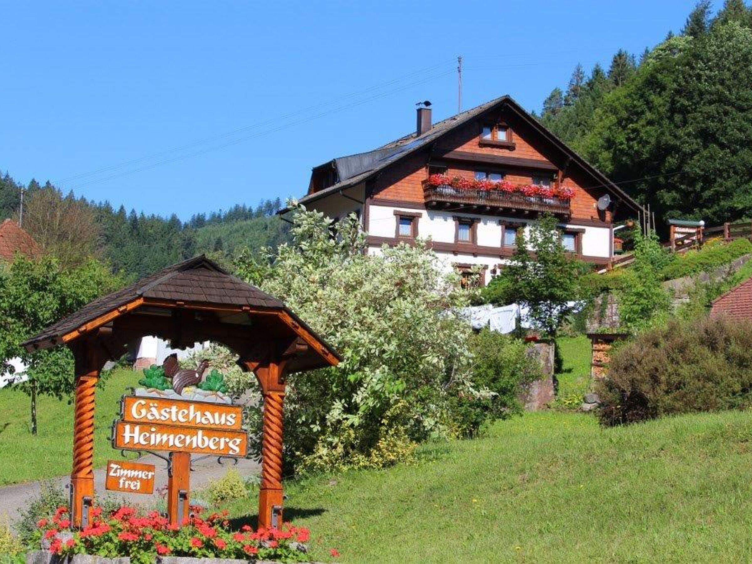 A traditional wooden building with a sign indicating 'Gästehaus Heimenbergs' and 'Zimmer frei' (rooms available).