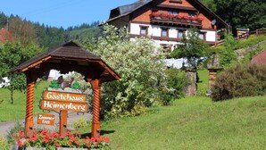 Un bâtiment traditionnel en bois, sur lequel on peut lire une enseigne indiquant « Gästehaus Heimenbergs » et « Zimmer frei » (chambres disponibles).