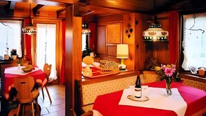 Un restaurant au décor intérieur en bois, avec des nappes rouges et une bouteille de vin posée sur la table.