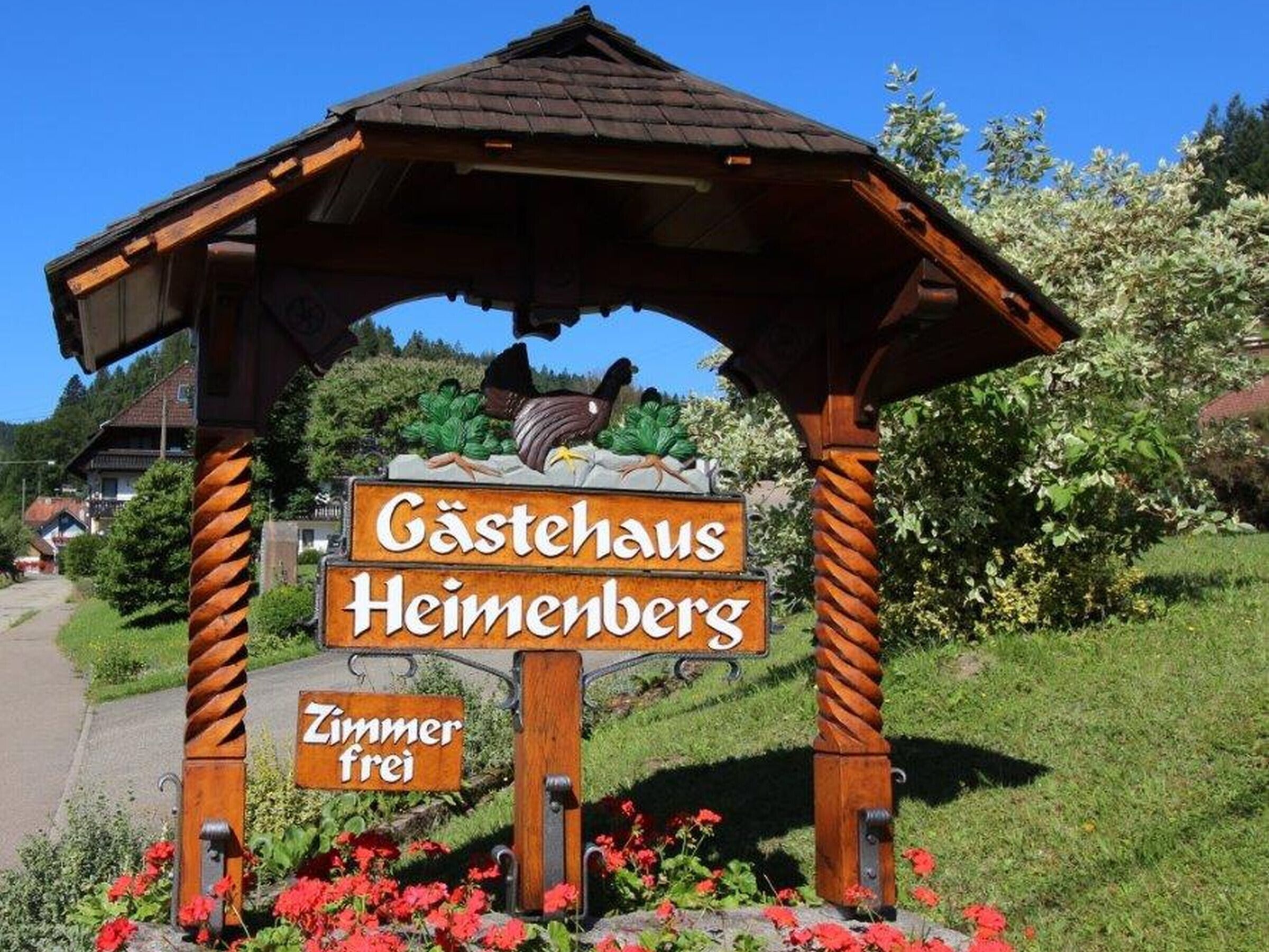 A wooden sign with 'Gästehaus Heimenberg' and 'Zimmer frei' indicating a guesthouse with available rooms.