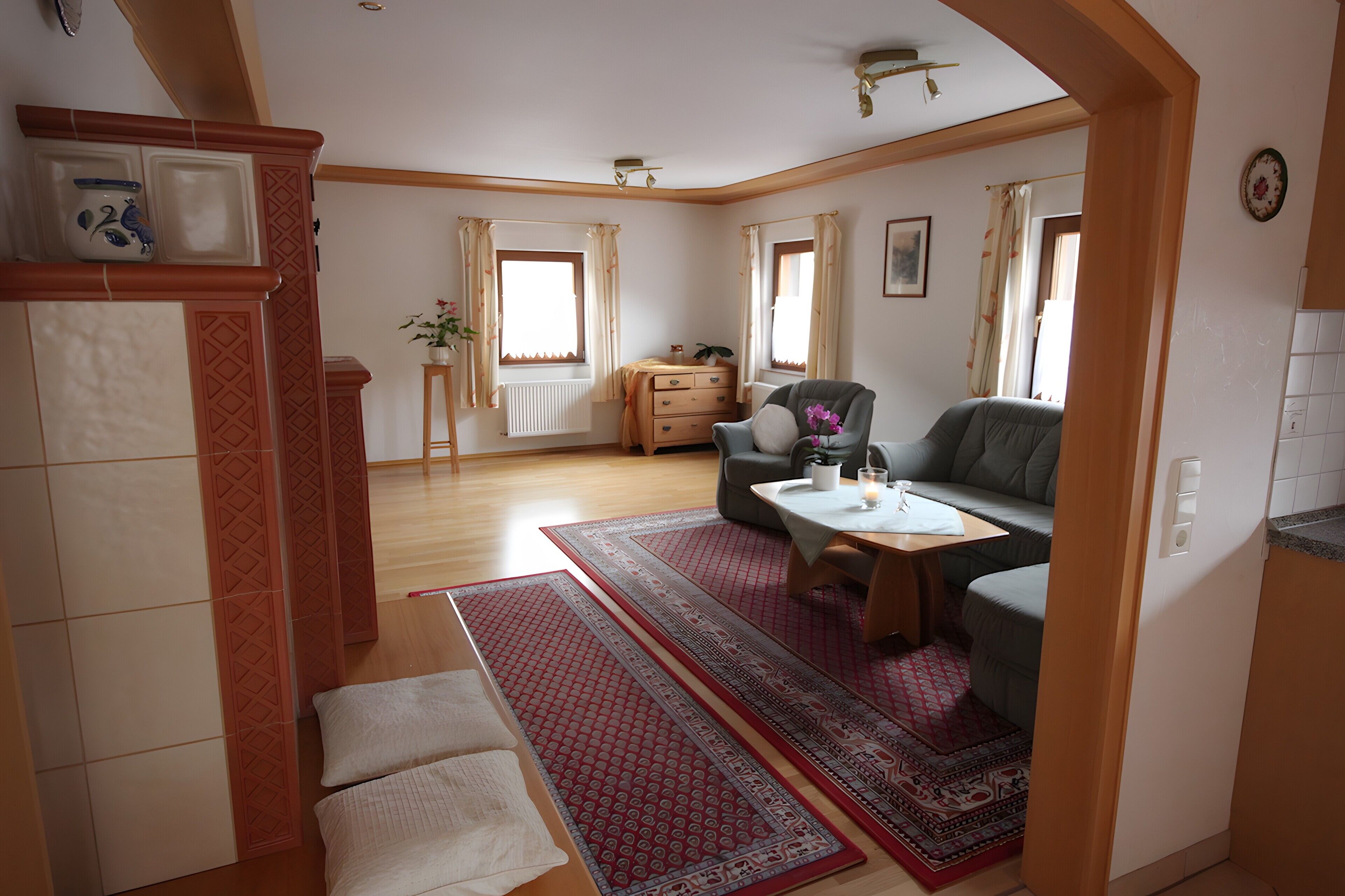 Un salon comprenant un canapé, une table basse, un fauteuil, un radiateur et une fenêtre avec des rideaux.
