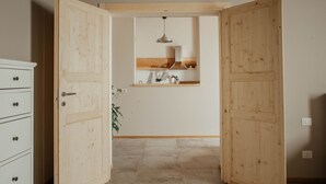 A room with a wooden door, a white dresser, a hanging light fixture, and a tiled floor. - Holiday Home 'La Cocca Home' with Shared Garden and Wi-Fi (Bellinzago Novarese)