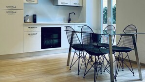 A modern kitchen with white cabinets, a black countertop, and a dining area with a table and chairs.