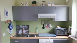A kitchen with grey cabinets, a Bosch dishwasher, a microwave, and various utensils hanging on the wall. - Ferienwohnung in St. Peter-Ording (St. Peter-Ording)