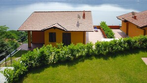Uma casa com telhado de cerâmica, varanda e vista para um lago e montanhas.