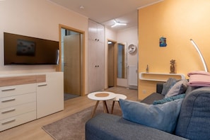 A modern living room with a sofa, a TV, a small round table, and a wooden cabinet.