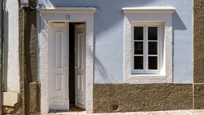 Um edifício com porta e janela brancas, número 10, e uma rua de paralelepípedos.