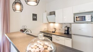 Eine moderne Küche mit weißen Schränken, einer Edelstahlspüle, einer Mikrowelle und einer Kaffeemaschine.