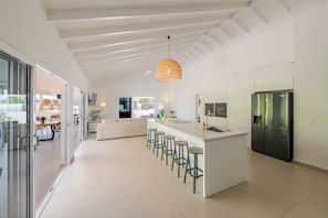 A modern kitchen with a central island, bar stools, and a built-in refrigerator.
