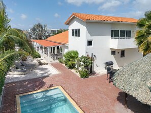 Propiedad residencial con piscina, mobiliario exterior y zona de patio techada.