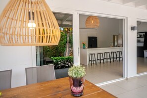 Una cocina moderna con un refrigerador negro, un comedor con una mesa de madera y una lámpara colgante.