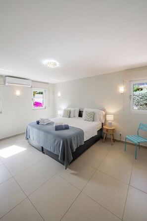 A bedroom with a bed, bedside table, chair, and window.