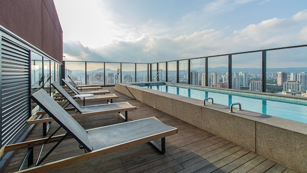 Un espace piscine sur le toit, avec des chaises longues et une vue sur la ville.