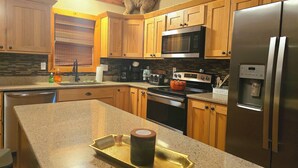 Una cucina con mobili in legno, un frigorifero in acciaio inox, un forno a microonde e un fornello.