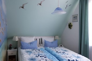 A bedroom with a bed, bedside tables, a lamp, and a hanging light fixture.