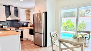 A modern kitchen with white cabinets, a stainless steel refrigerator, and a wooden countertop. - Modern Oasis with Pool + Putting Green (Pinellas Park)