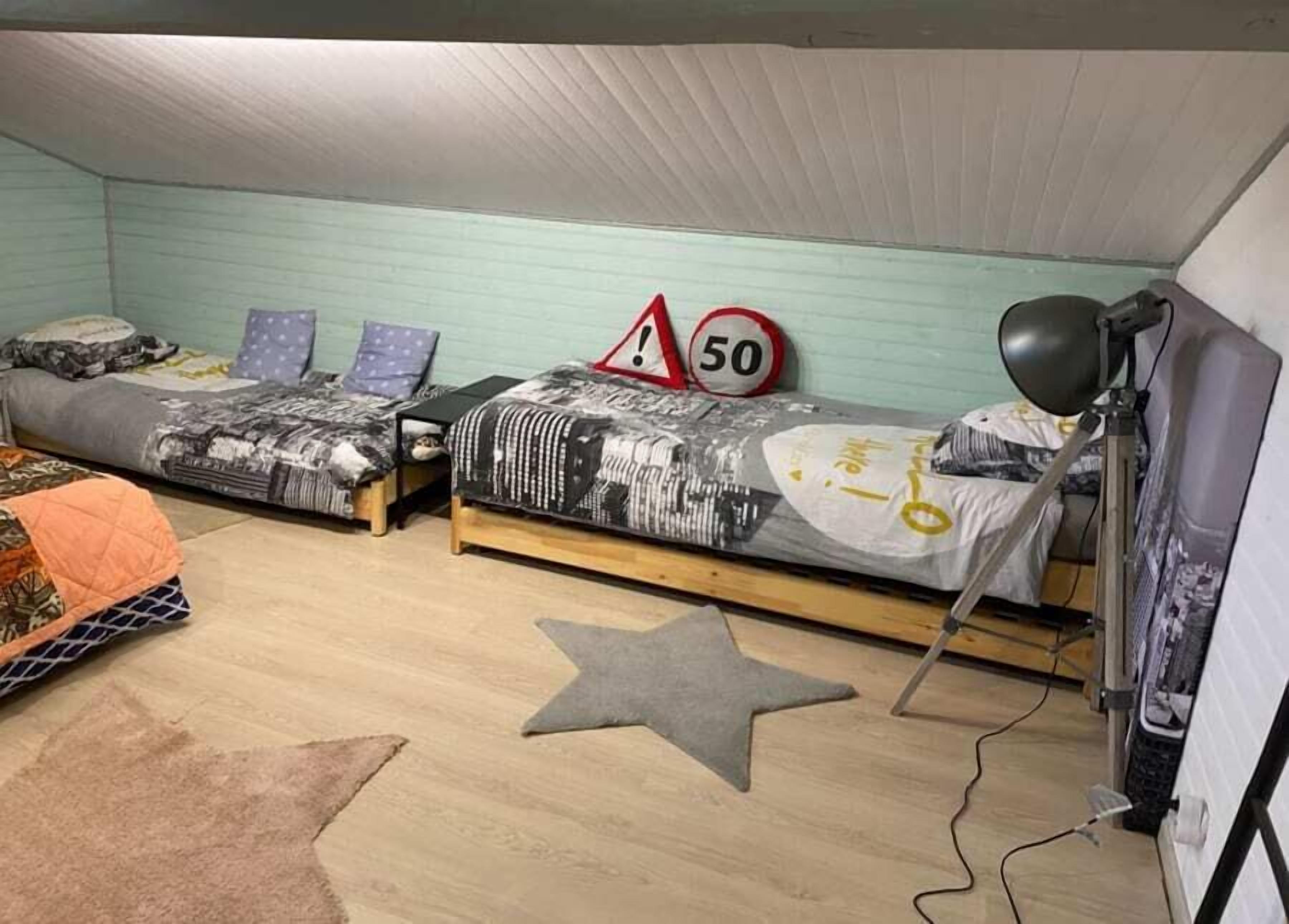 Een studentenkamer met twee bedden, een rug in de vorm van een ster, een bureau en een lamp.