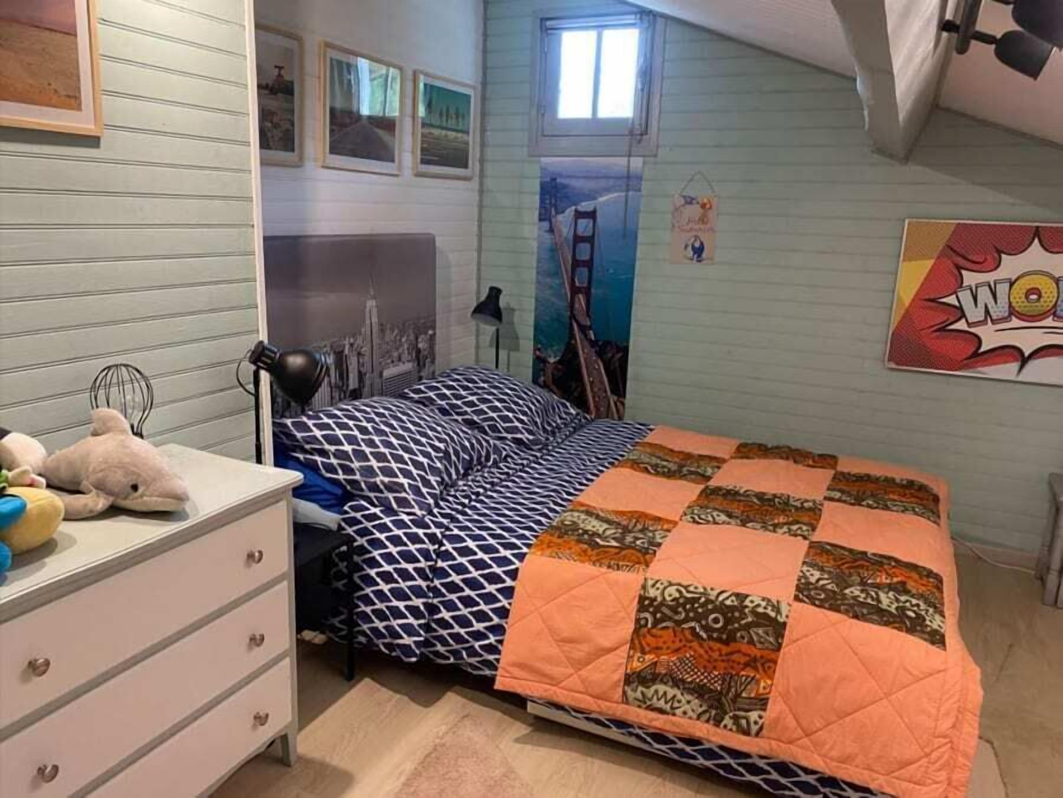 A bedroom with a bed, dresser, and wall decorations.