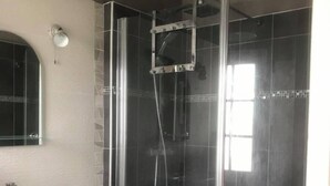Un bagno moderno con doccia vetrata, lavandino bianco e specchio sopra.