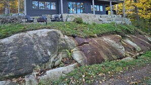 Ein modernes, zweistöckiges Haus mit großen Fenstern und einer Steinmauer.