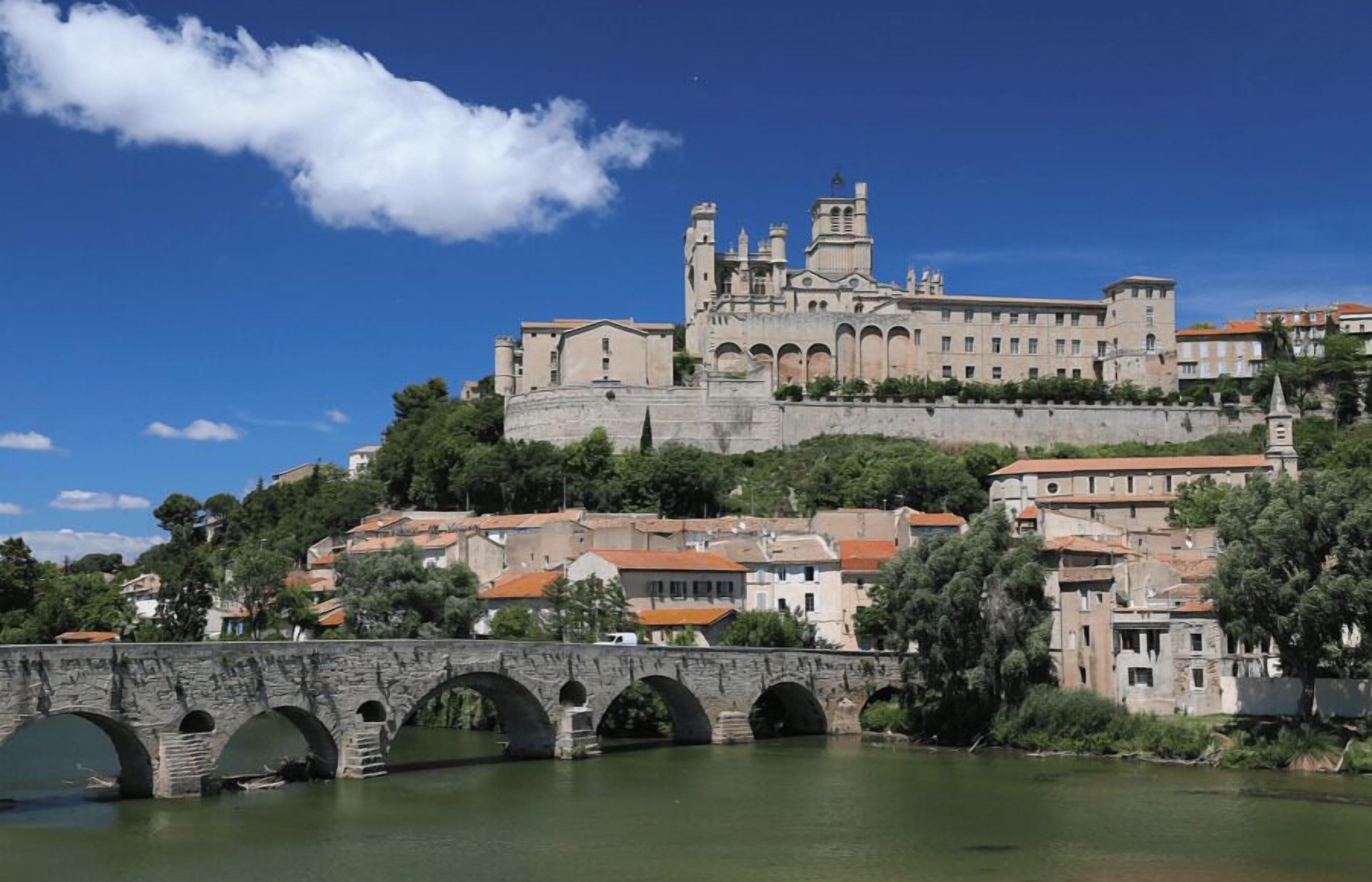 A historic building with multiple arches and a bridge in the foreground.
