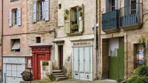 A building with a sign for 'du Cuir du Bois' and a 'Musée de la Porte' sign. - Annick Mobilhome (Vias)