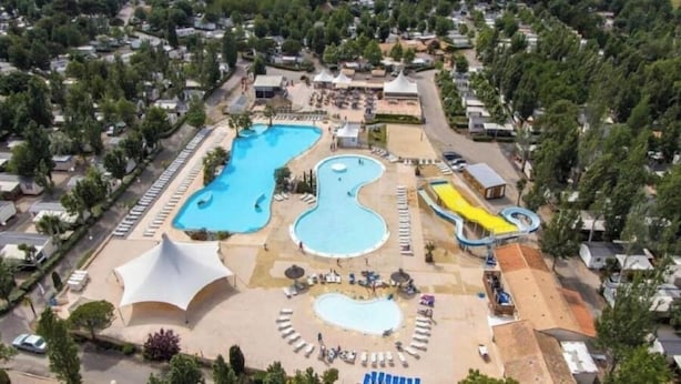 An aerial view of a resort with multiple swimming pools, a water slide, and a covered area with lounge chairs. - Annick Mobilhome (Vias)