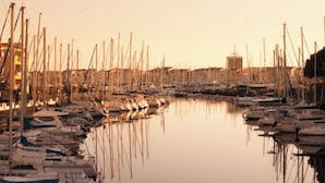 A marina with numerous boats docked, calm water, and buildings in the background. - Annick Mobilhome (Vias)