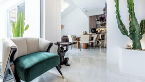 A modern living room with a green sofa, a cactus plant, and a minimalist kitchen in the background. - New and Luxurious Villa Los Olivos  (Adeje)