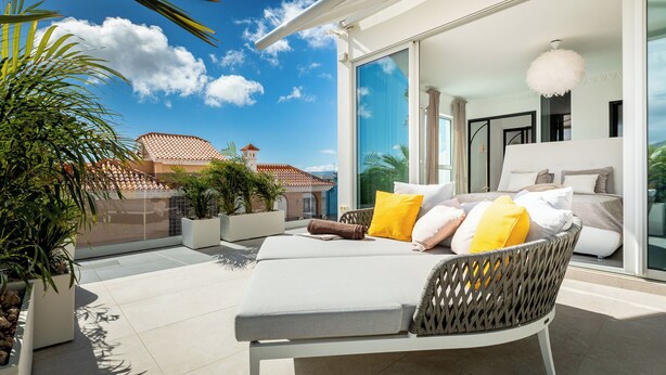 A modern outdoor lounge area with a cushioned seating arrangement, a glass door leading to a bedroom, and potted plants. - New and Luxurious Villa Los Olivos  (Adeje)