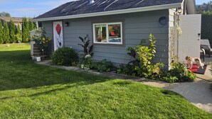 Ein eingeschossiges Haus mit geneigtem Dach, Solaranlage, einer kleinen Veranda und einem gepflegten Rasen.