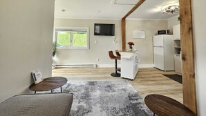 Eine moderne Küche mit weißen Geräten, Holzbalkendecke und einem flachbildfernseher, der über der Arbeitsplatte angebracht ist.