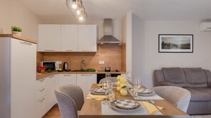 Une cuisine moderne avec des meubles blancs, un plan de travail en bois et une table à manger pour quatre personnes.