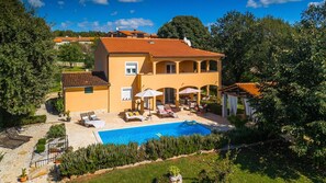 Une maison à deux étages avec une piscine, un espace salon extérieur et un jardin.