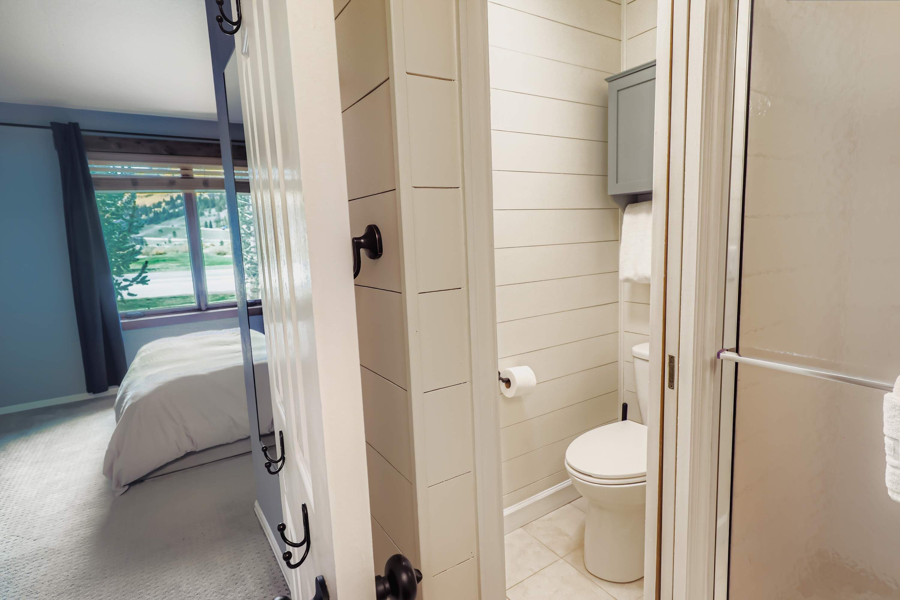 Un dormitorio con cama, un baño con inodoro y ducha, y vistas al exterior a través de una ventana.